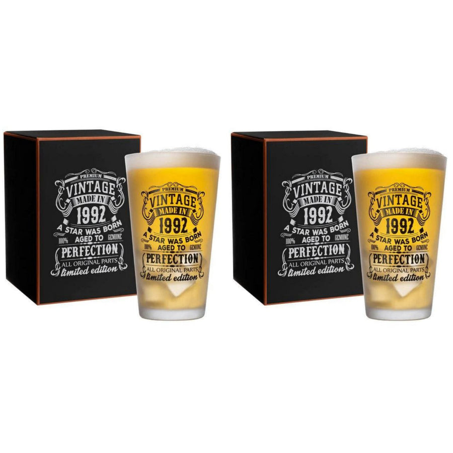 Two beer glasses with vintage design and text, placed in front of their packaging box on a white background.