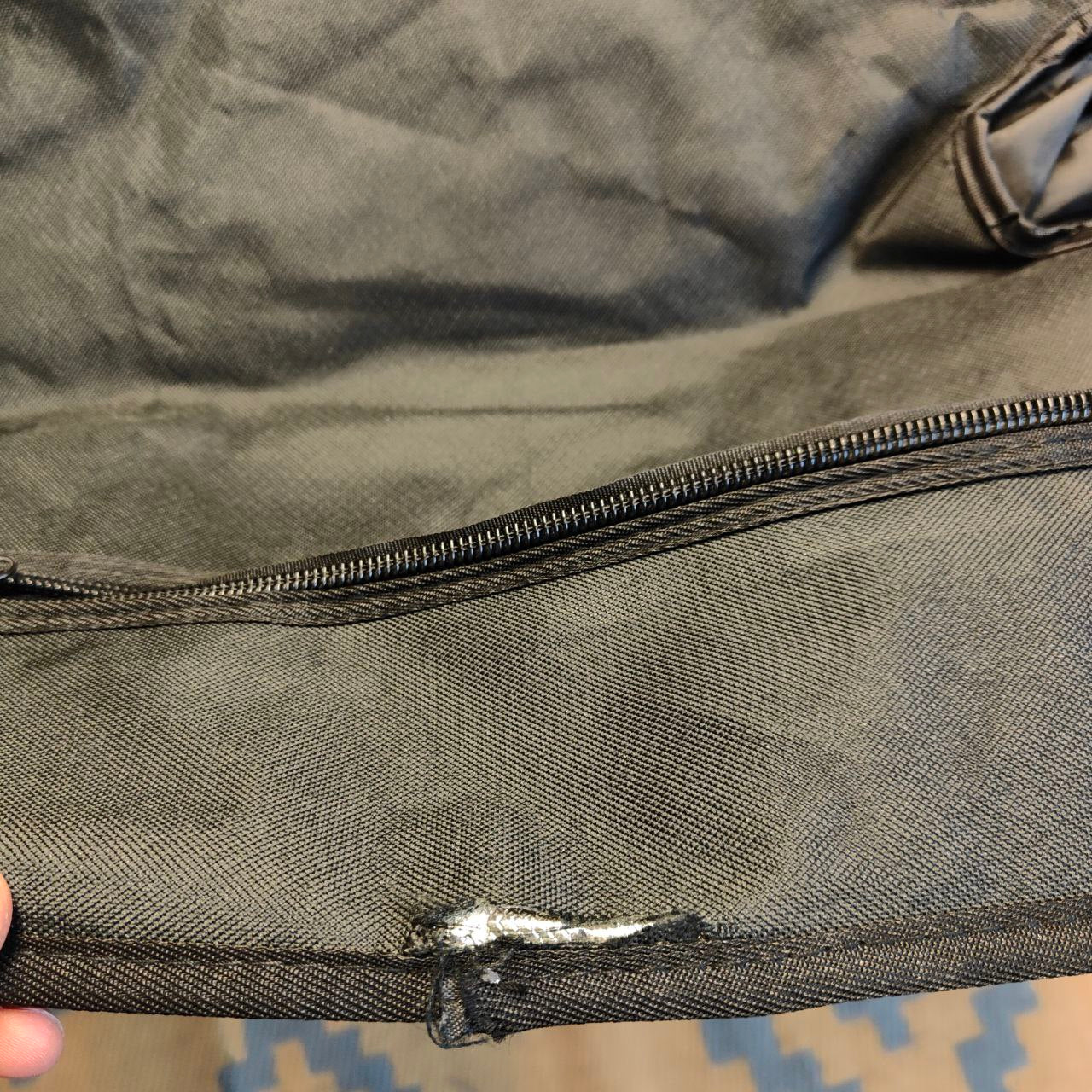 Close-up of a dark gray bag with a zipper, showing wear and tear.