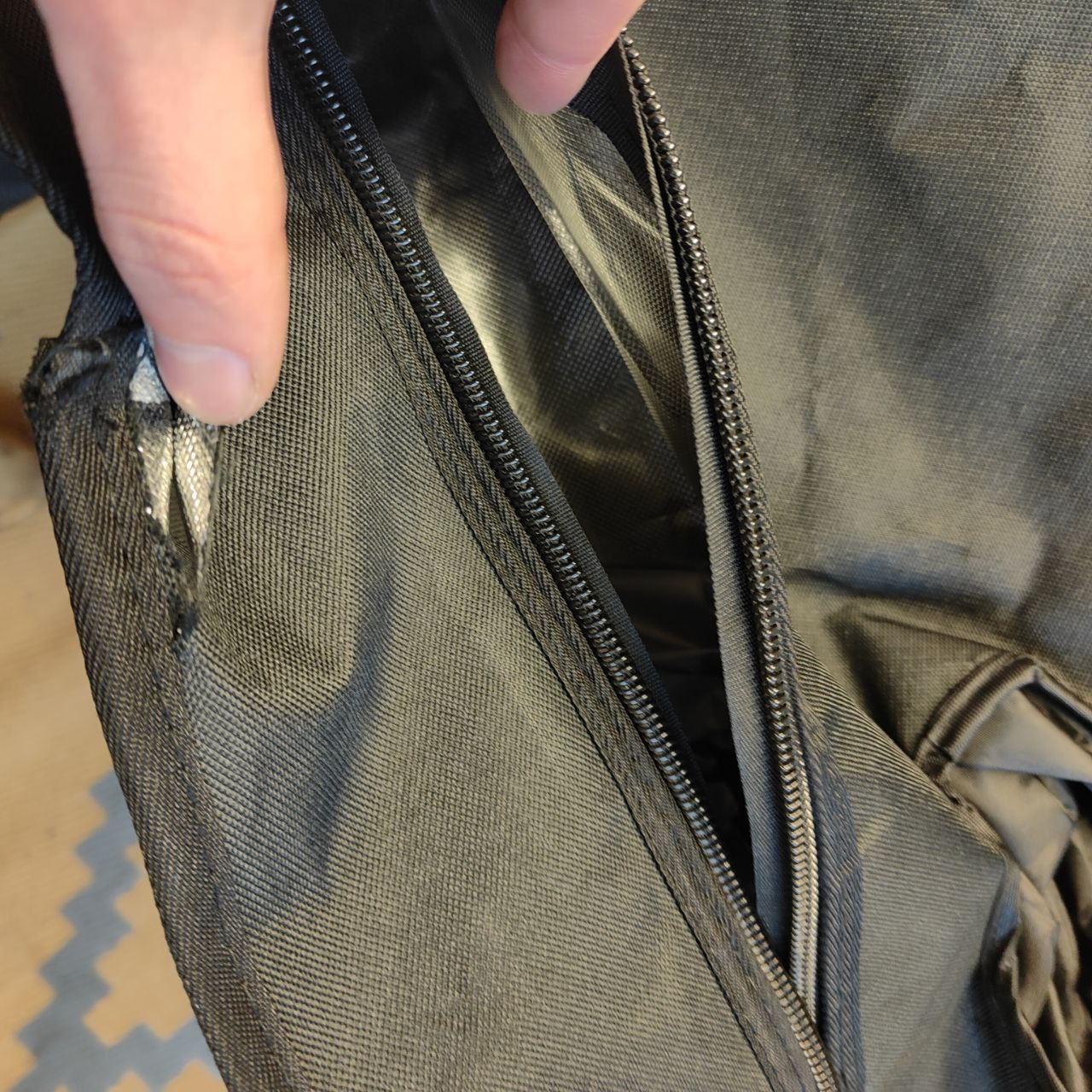 Close-up of a green bag with a zipper, showing wear and tear.