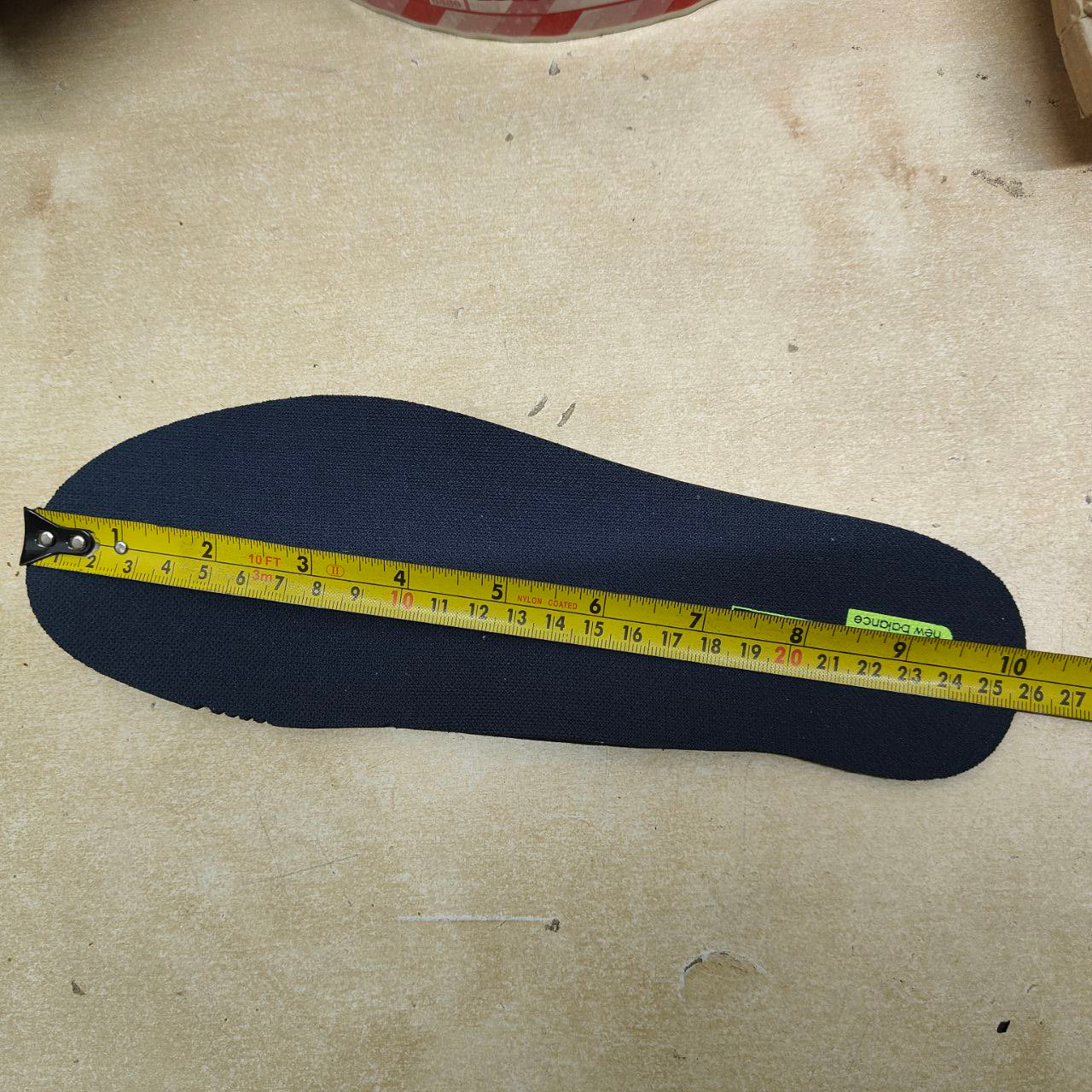 Black insole with a yellow measuring tape on a beige surface