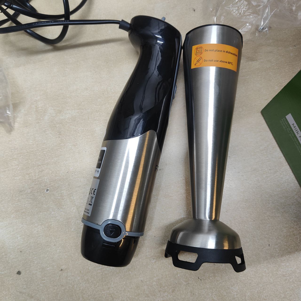 Black and silver immersion blender parts on a beige surface