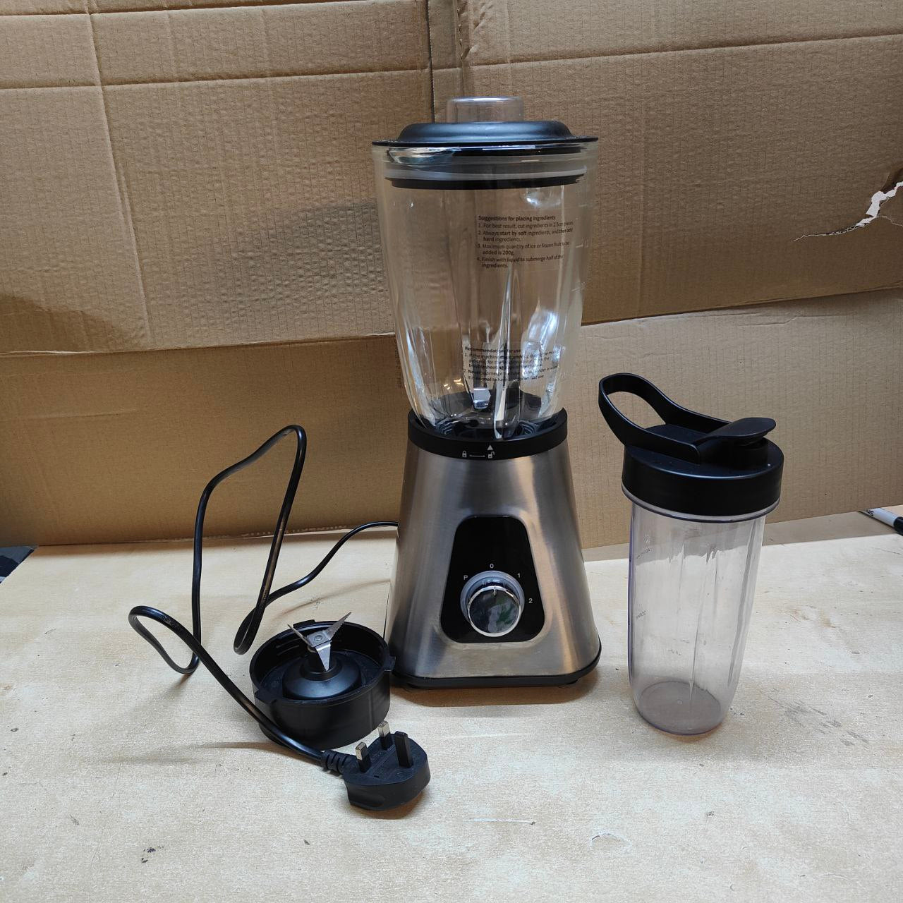 Blender with clear container and black lid on a beige surface with cardboard background
