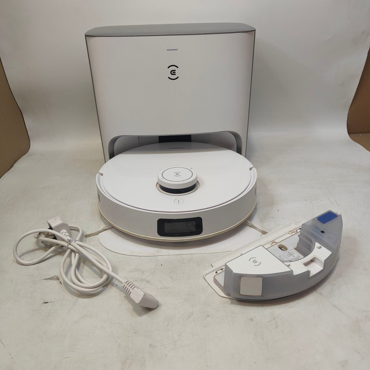 Robotic vacuum cleaner with charging station and cable on a white background
