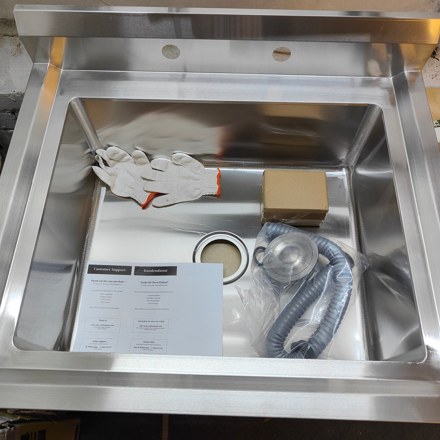 Stainless steel sink with gloves, paper, and hose inside
