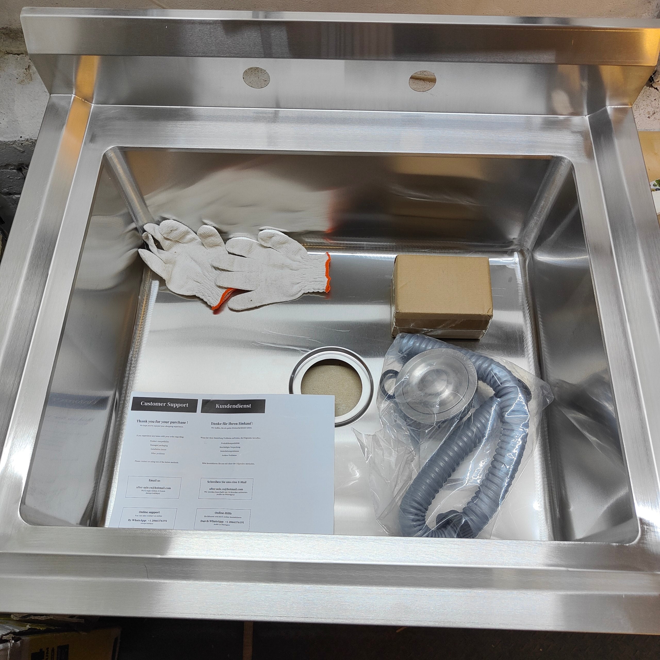 Stainless steel sink with gloves, paper, and hose inside