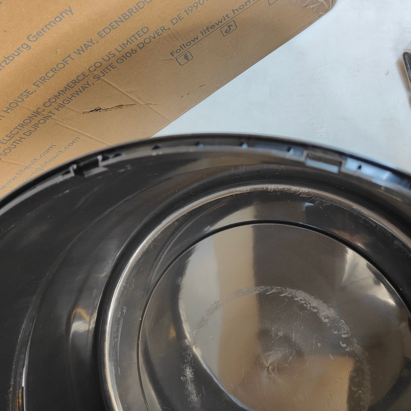 Close-up of a metallic container with a reflective surface, possibly part of a larger appliance or equipment.