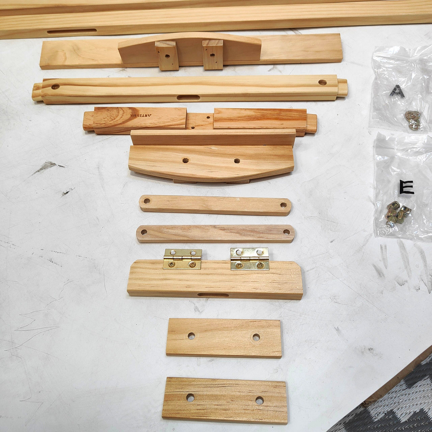 Wooden furniture assembly parts on a white surface with hardware.
