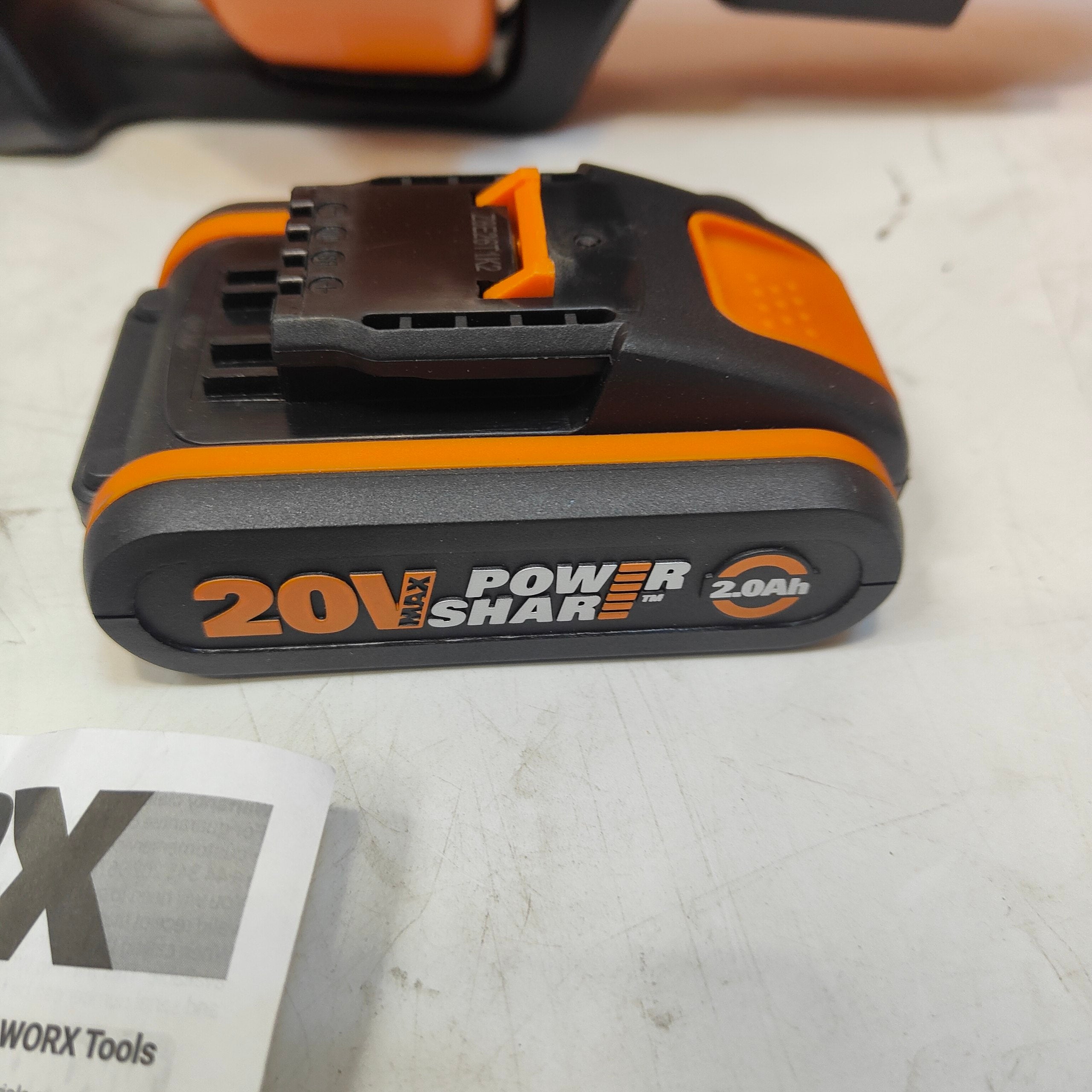 20V Power Share battery on a white surface with a WORX tool box in the background.