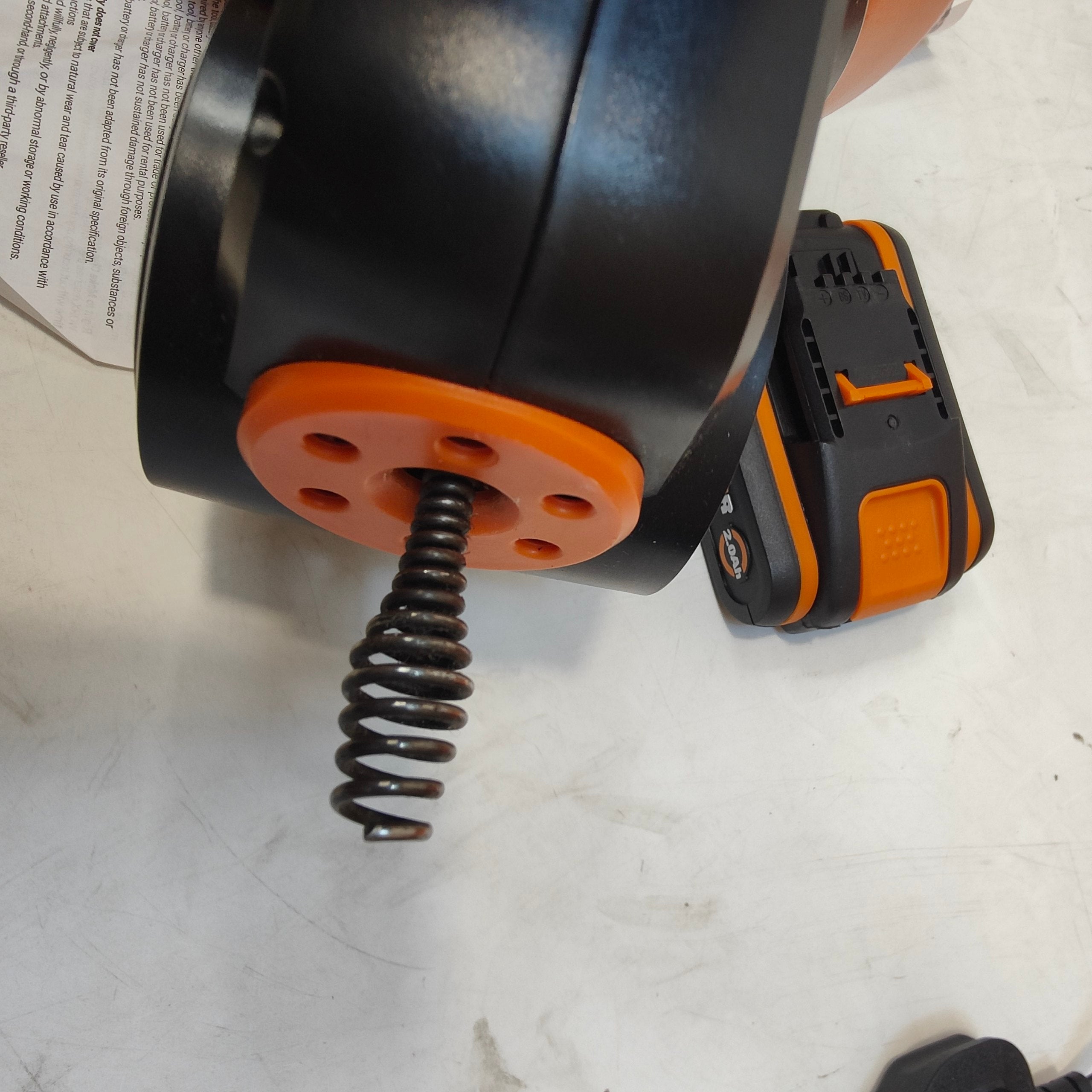 Black and orange cordless drill on a white surface