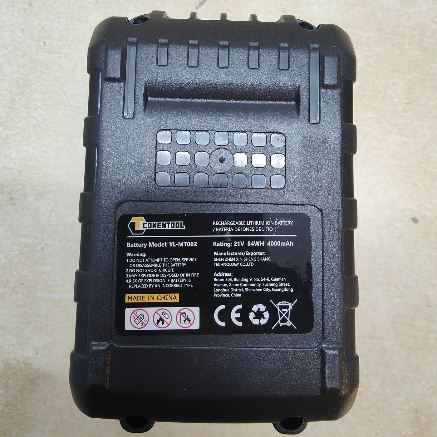 Black battery pack with visible branding and specifications on a beige surface