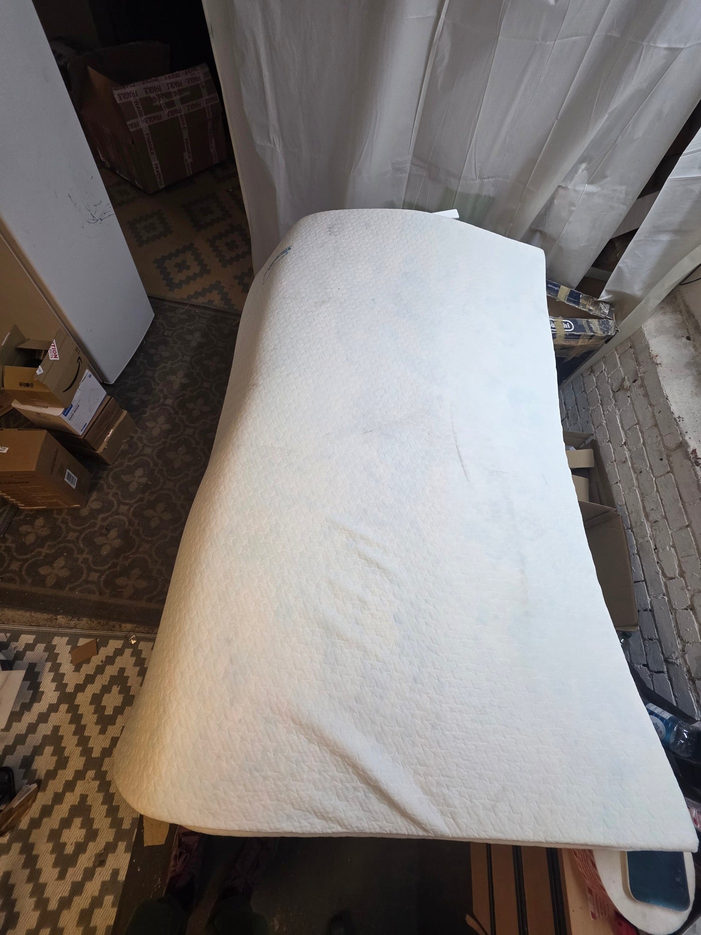 Mattress on a stand in a room with a rug and door in the background