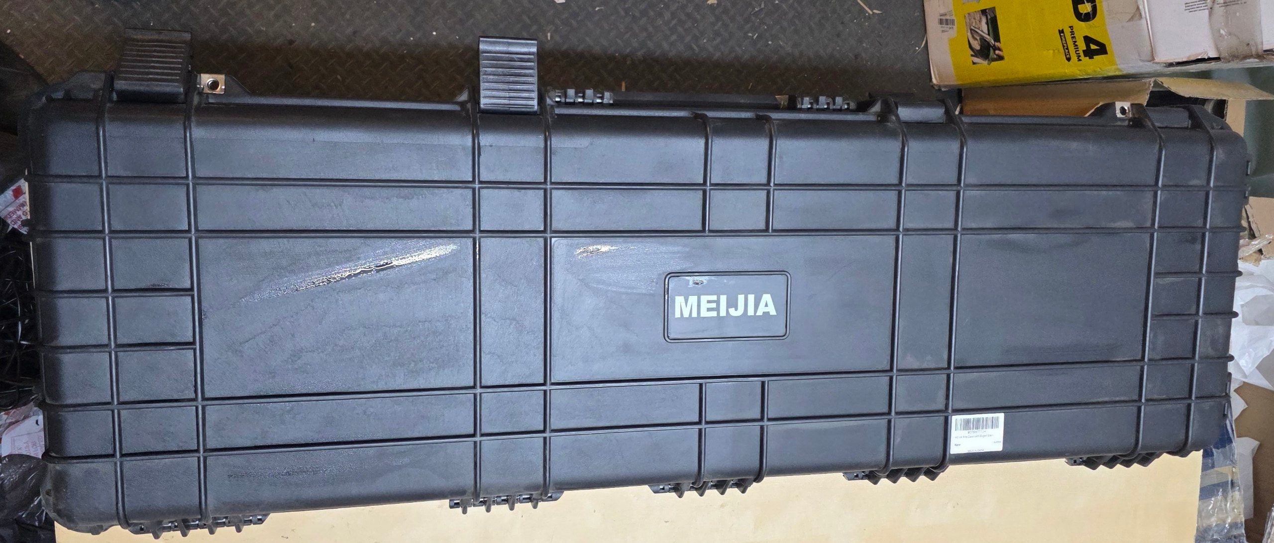 Large black MEIJIA toolbox on a wooden surface with a cardboard box in the background.