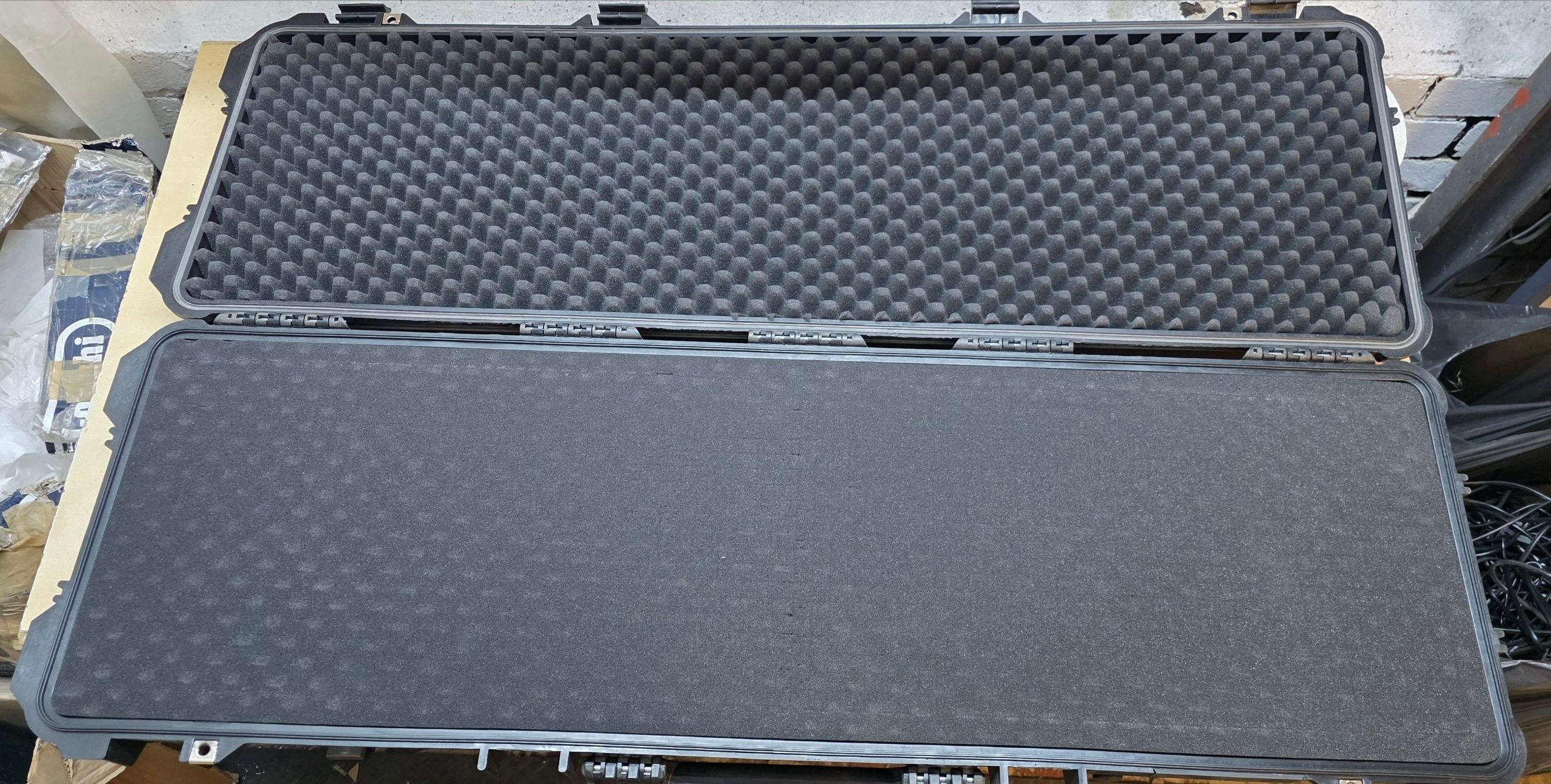 Large black foam-lined case on a wooden surface