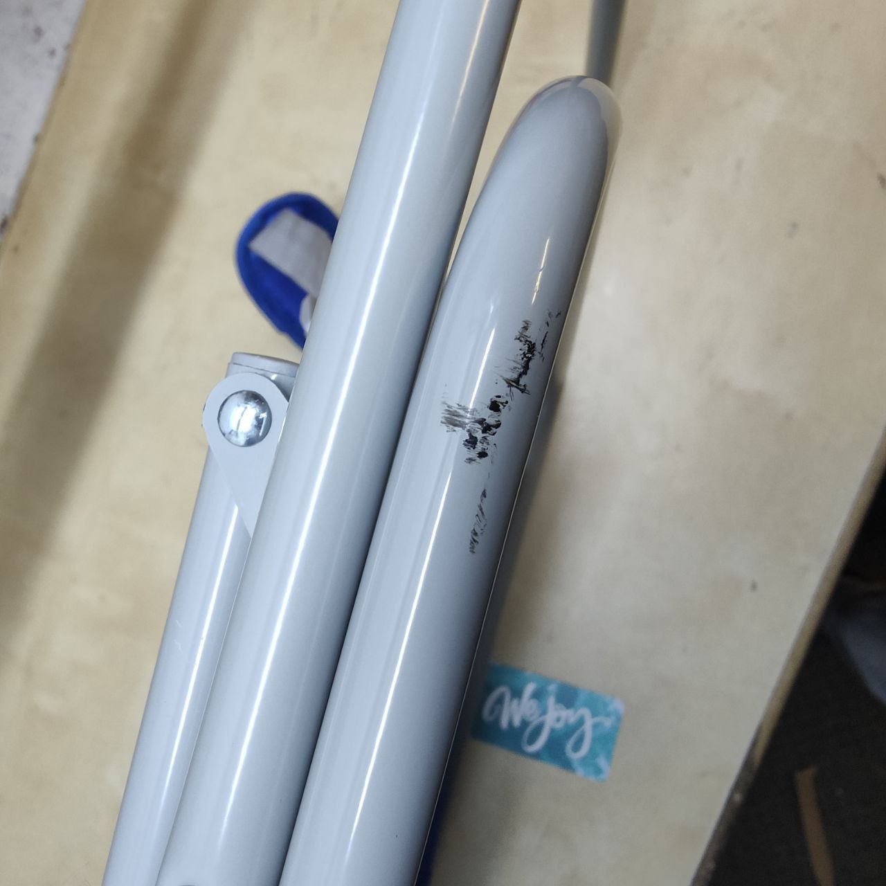 Two gray metal pipes with a blue tag on a beige surface