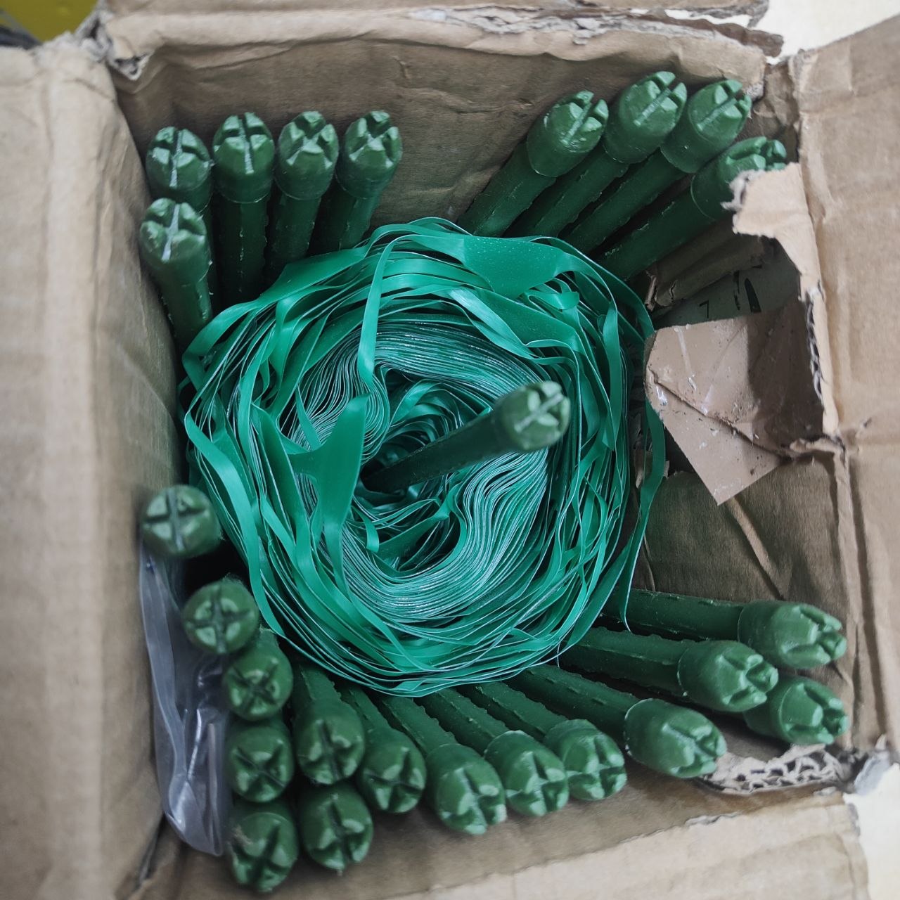 Green plastic straps and connectors in a cardboard box