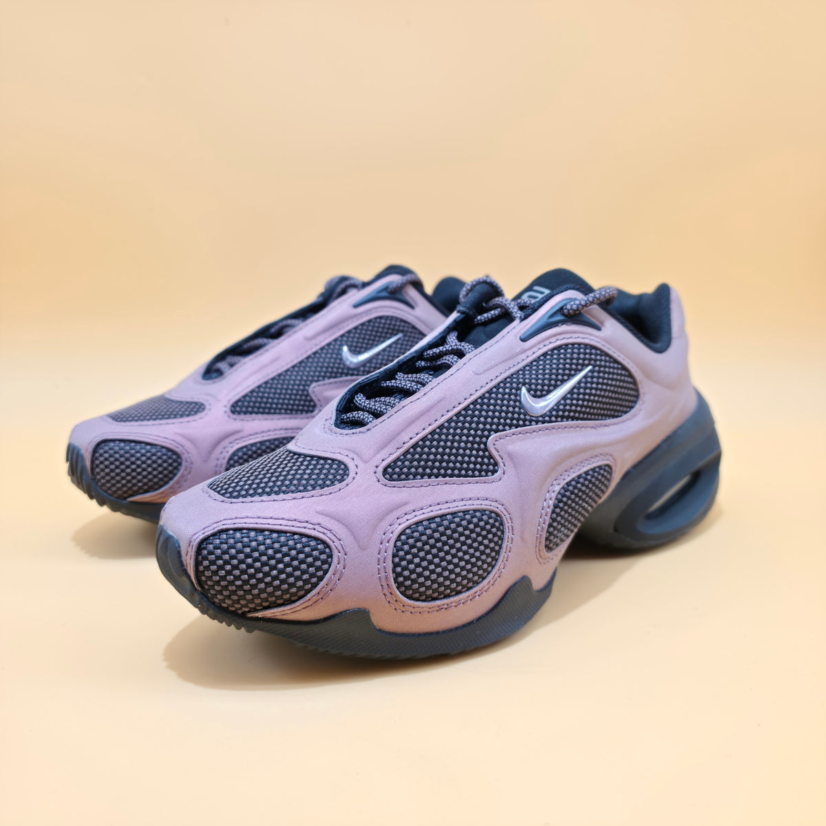 A pair of Nike Air Max 2013 sneakers in lavender purple and dark navy blue, shown on a warm beige background.