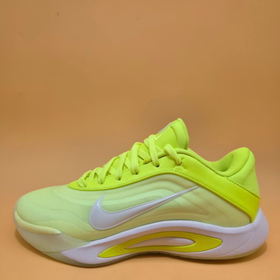 A Nike basketball shoe in neon yellow and light green with a white swoosh and white sole, photographed against a solid tan background.