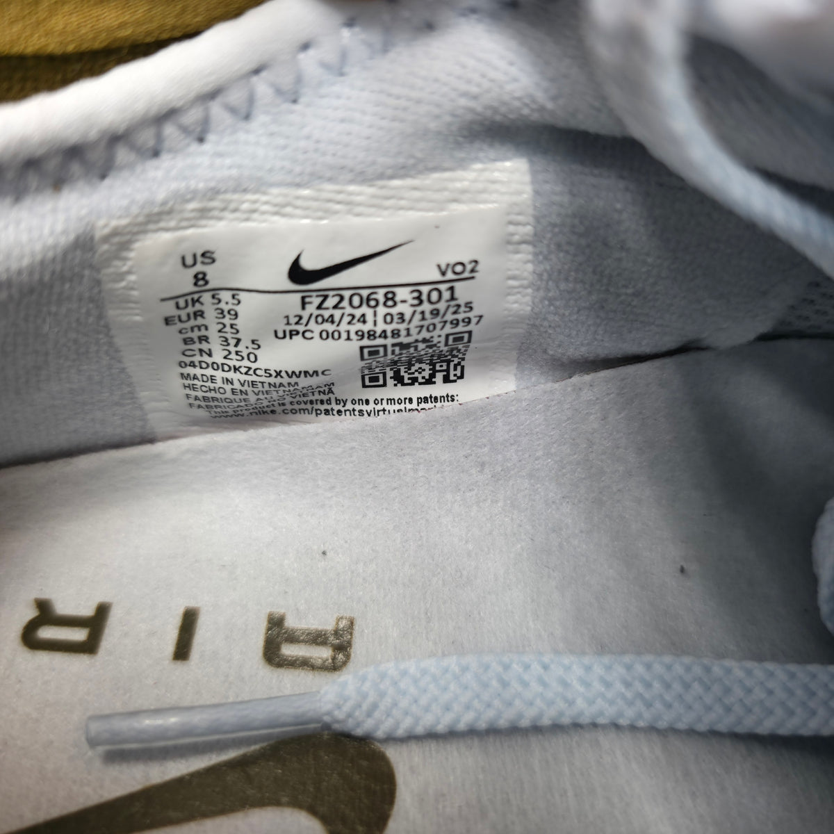 Close-up of a Nike garment interior label reading FZ2068-301, with visible Nike swoosh and size information on white fabric.