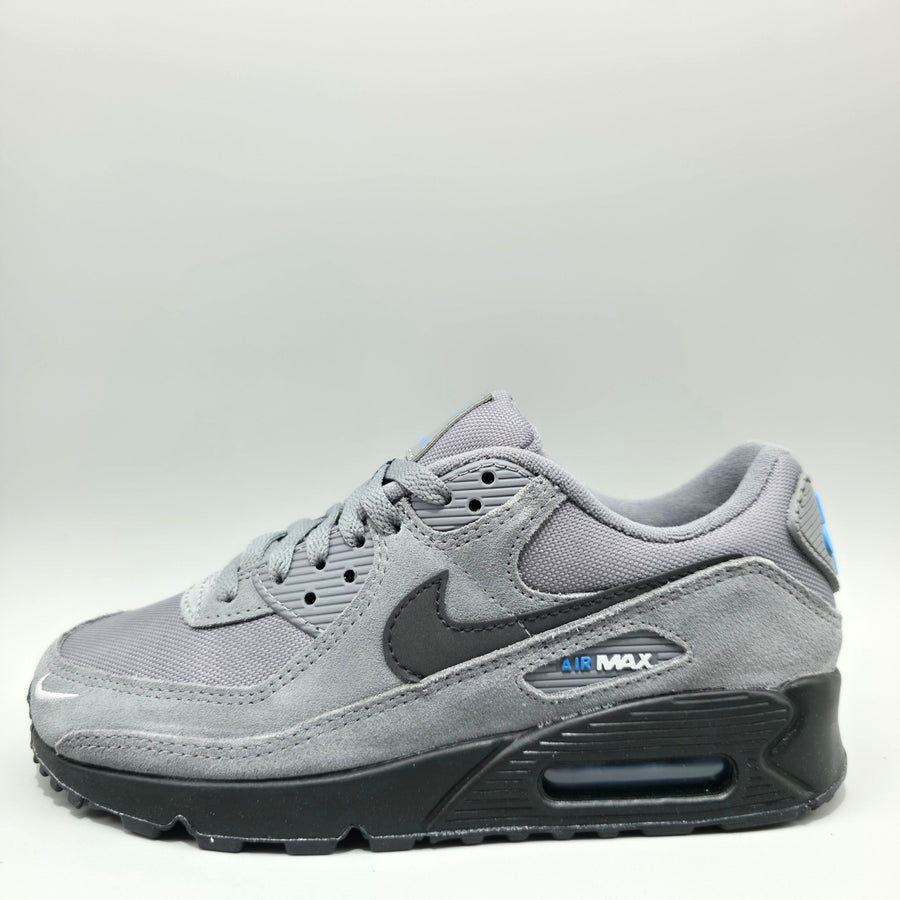 A Nike Air Max sneaker in gray suede and mesh with a dark gray Swoosh, a black sole, and a small blue accent on the heel.