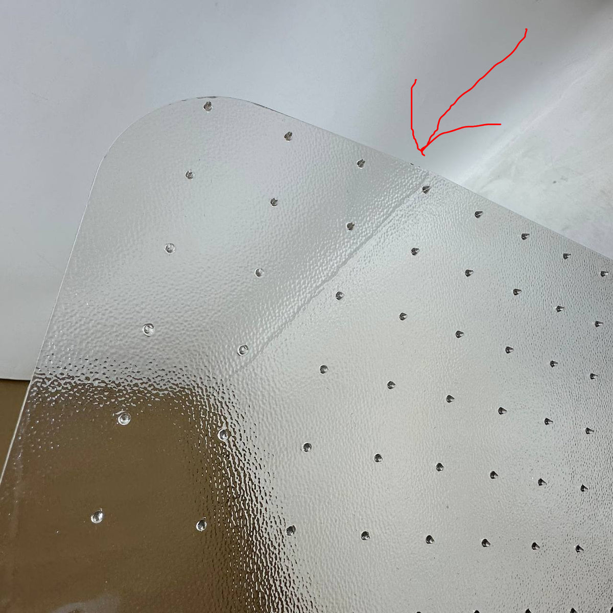 A close-up of a transparent textured sheet with small evenly spaced circular holes, shown against a plain light background.