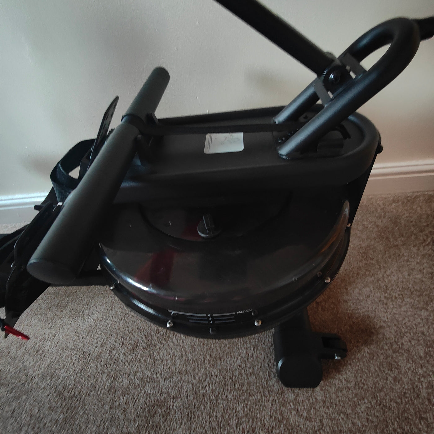 Black exercise bike on a carpeted floor with a neutral wall background
