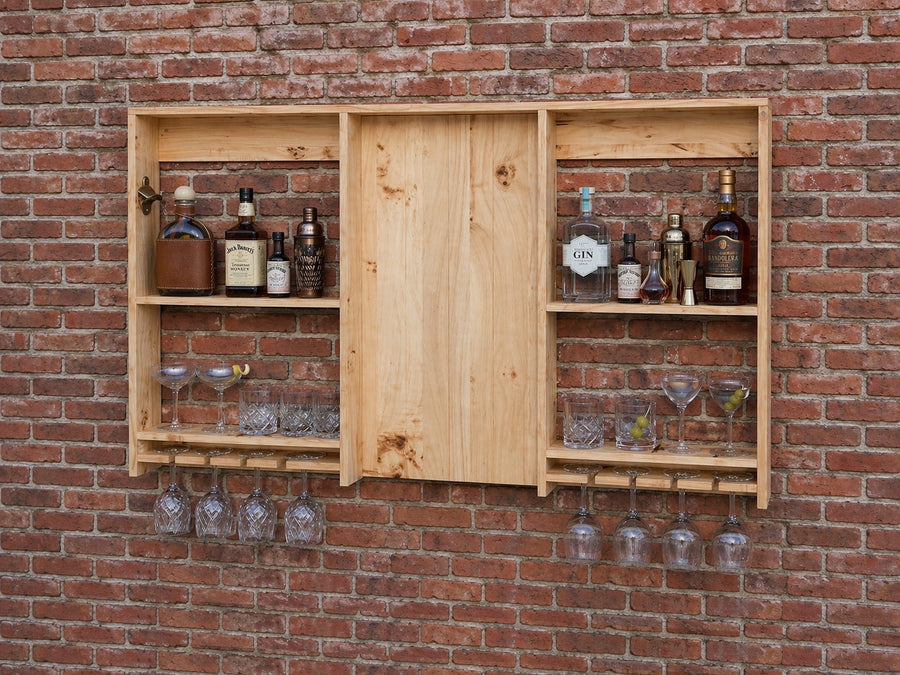 Wooden wall-mounted bar cabinet with bottles and glasses against a brick wall.