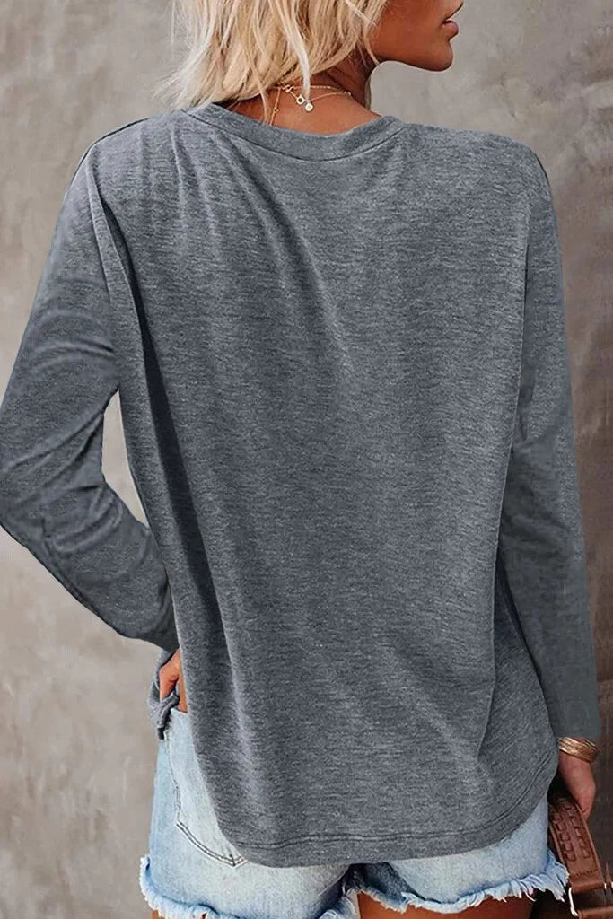 Person wearing a gray long-sleeve top and denim shorts against a neutral background