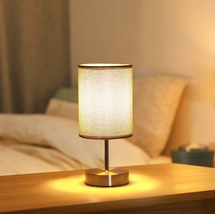 Table lamp on a wooden surface with a soft glow in a bedroom setting